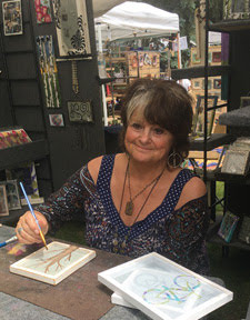 Barbara Downey at her artists' desk painting a new earring holder.