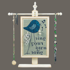 Hand-painted Earring Holder with Sing Your Own Song Design — solid wood white distressed frame with fiberglass screen earring display area hanging on necklace stand. Handmade in Michigan.